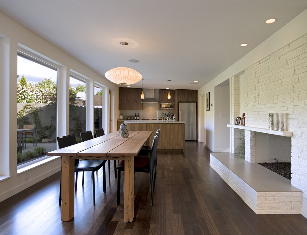 Cette photo montre une salle à manger ouverte sur le salon moderne avec un manteau de cheminée en brique et un mur blanc.