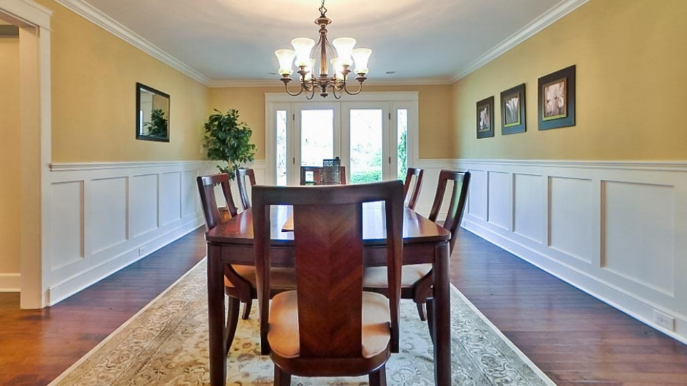 Example of a large 1950s dark wood floor, brown floor and wainscoting enclosed dining room design in Cleveland with beige walls