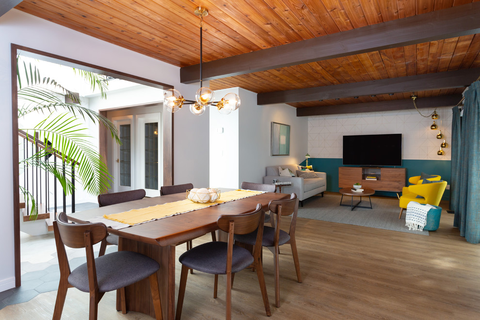Aménagement d'une salle à manger ouverte sur la cuisine rétro de taille moyenne avec un mur gris, un sol en bois brun, aucune cheminée et un sol marron.