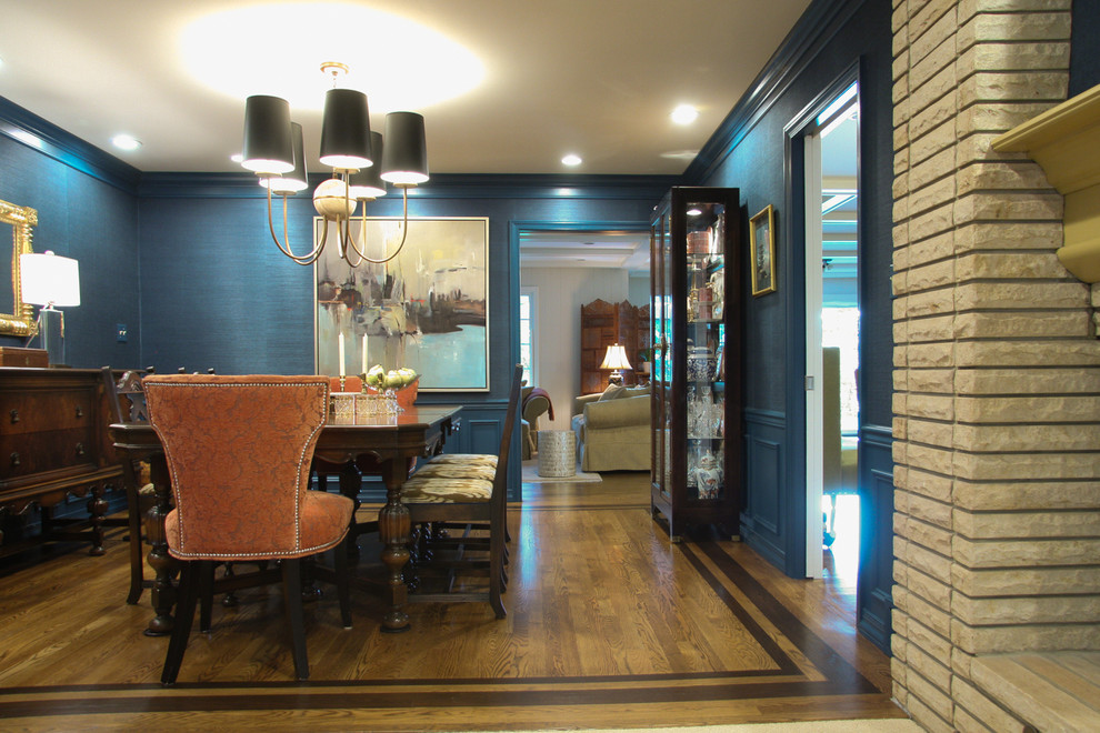 Foto di una sala da pranzo chic chiusa e di medie dimensioni con pareti blu, pavimento in legno massello medio, camino ad angolo, cornice del camino in mattoni e pavimento marrone