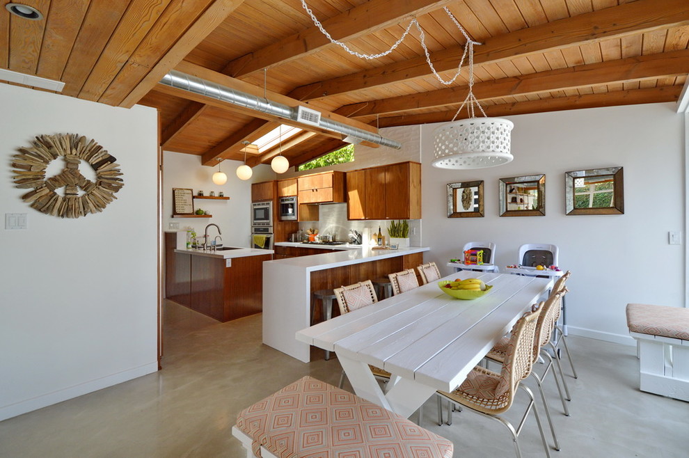 Ispirazione per una sala da pranzo aperta verso la cucina moderna di medie dimensioni con pareti bianche e pavimento in cemento