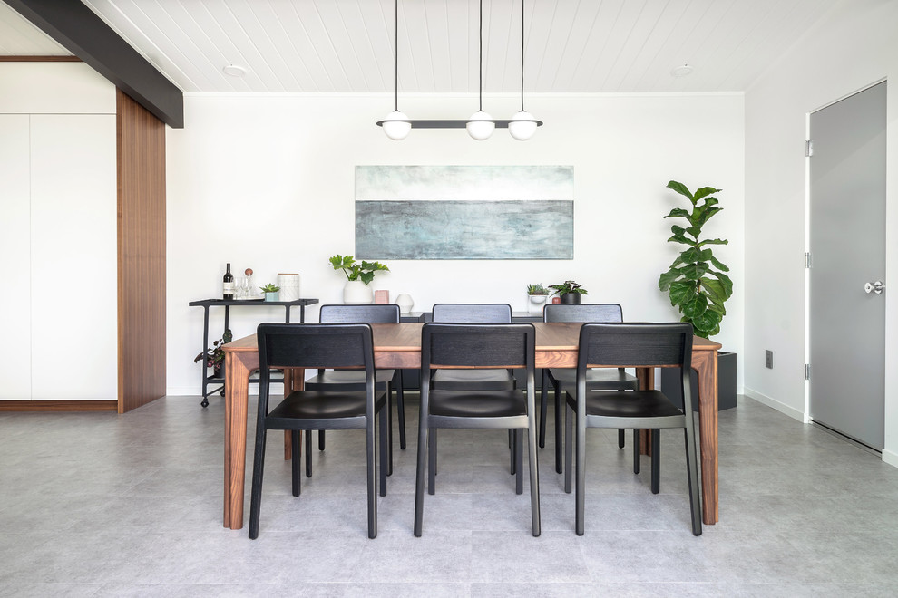 This is an example of a midcentury dining room in San Francisco with white walls and grey floors.
