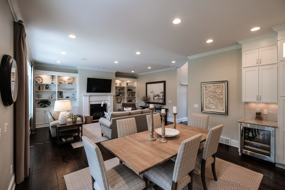 Exemple d'une grande salle à manger ouverte sur la cuisine chic avec un mur gris, parquet foncé, une cheminée standard, un manteau de cheminée en bois, un sol marron et éclairage.