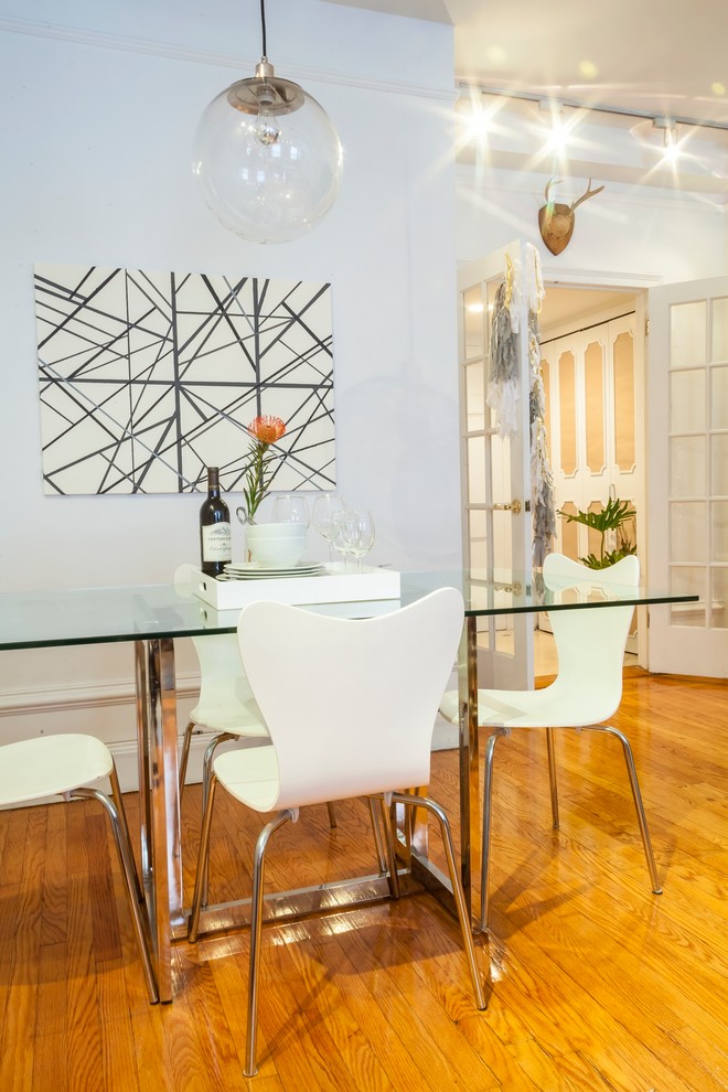 Idée de décoration pour une salle à manger ouverte sur le salon design de taille moyenne avec un sol en bois brun et un mur blanc.