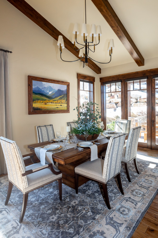 Example of a mountain style dark wood floor, brown floor, exposed beam and vaulted ceiling dining room design in Salt Lake City with beige walls