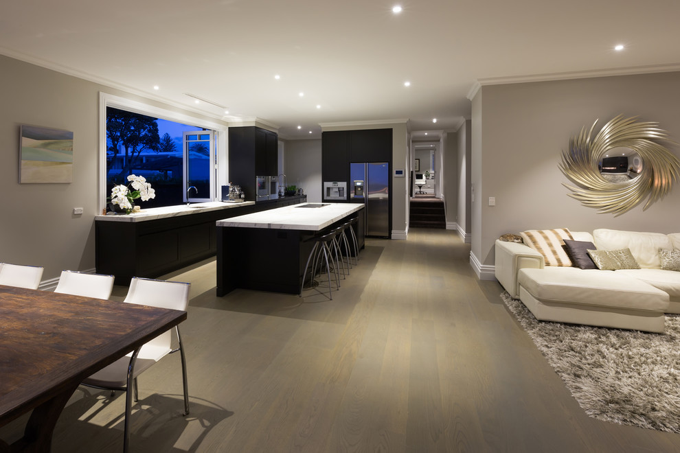 Aménagement d'une grande salle à manger ouverte sur la cuisine bord de mer avec parquet clair, un mur gris et une cheminée double-face.