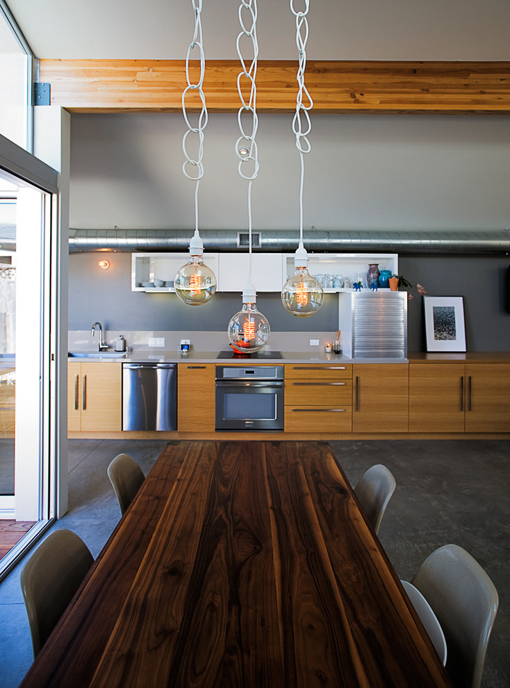 Cette image montre une petite salle à manger ouverte sur la cuisine minimaliste avec un mur gris et sol en béton ciré.