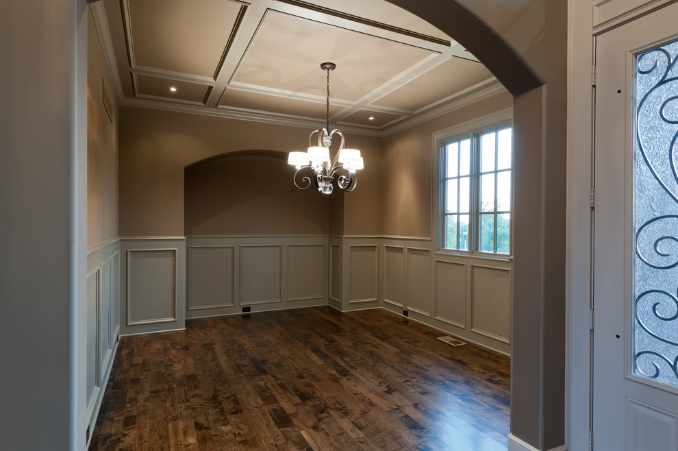 Geschlossenes, Großes Klassisches Esszimmer mit beiger Wandfarbe, dunklem Holzboden und braunem Boden in Kansas City