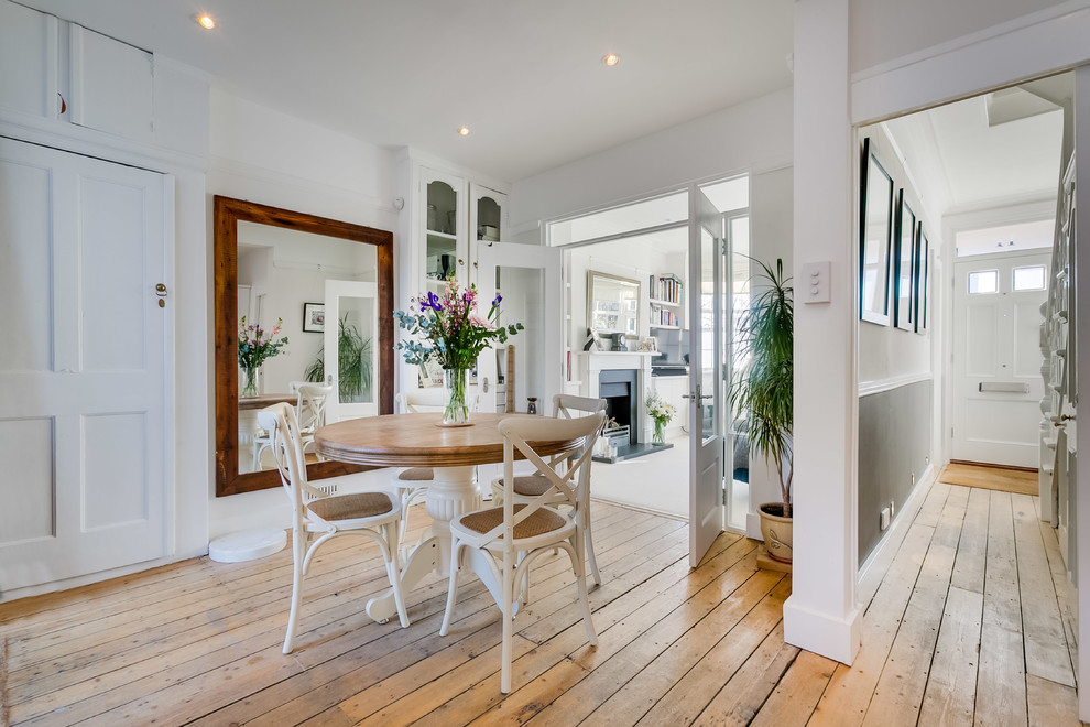 Example of a mid-sized transitional light wood floor and beige floor dining room design in London with white walls