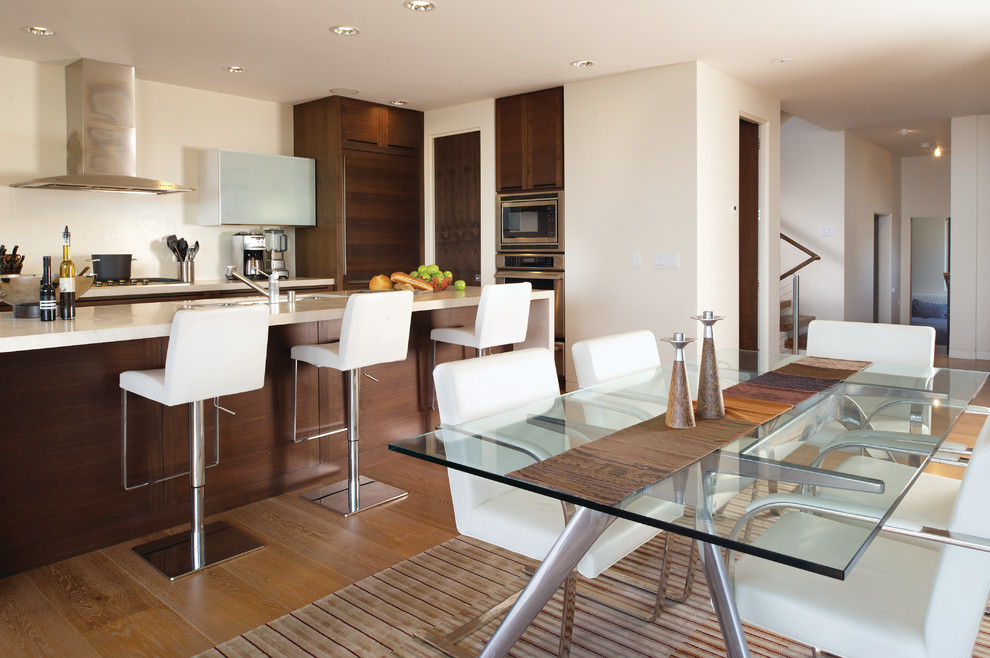 Idée de décoration pour une salle à manger ouverte sur la cuisine design avec un mur blanc et un sol en bois brun.