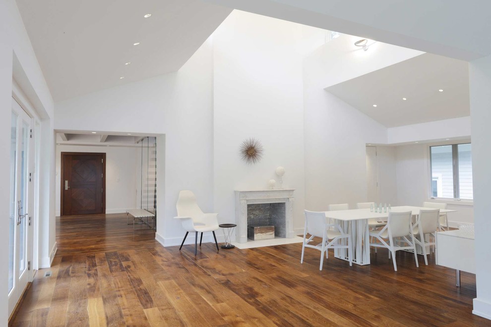 Inspiration pour une grande salle à manger design avec un mur blanc, un sol en bois brun, une cheminée standard et un manteau de cheminée en pierre.