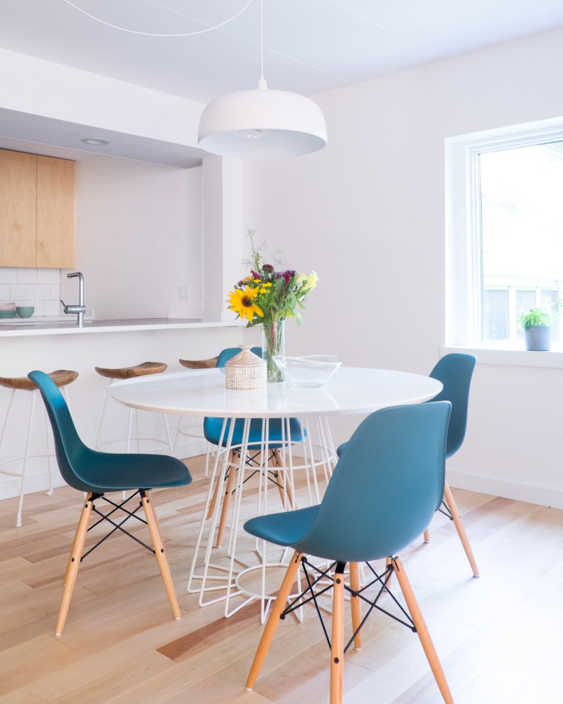 Immagine di una piccola sala da pranzo aperta verso la cucina scandinava con pareti bianche e parquet chiaro