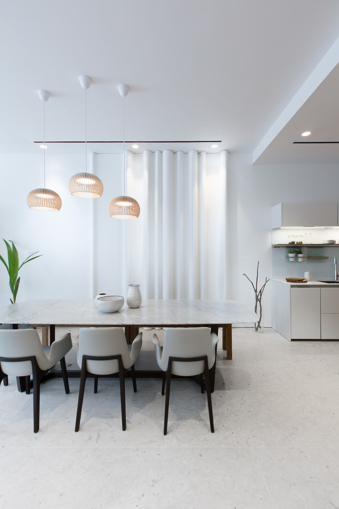 Exemple d'une salle à manger ouverte sur la cuisine moderne avec un mur blanc et un sol en calcaire.