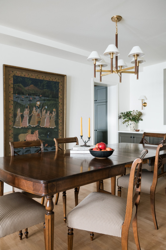 This is an example of a traditional dining room in Minneapolis with white walls, medium hardwood flooring and brown floors.