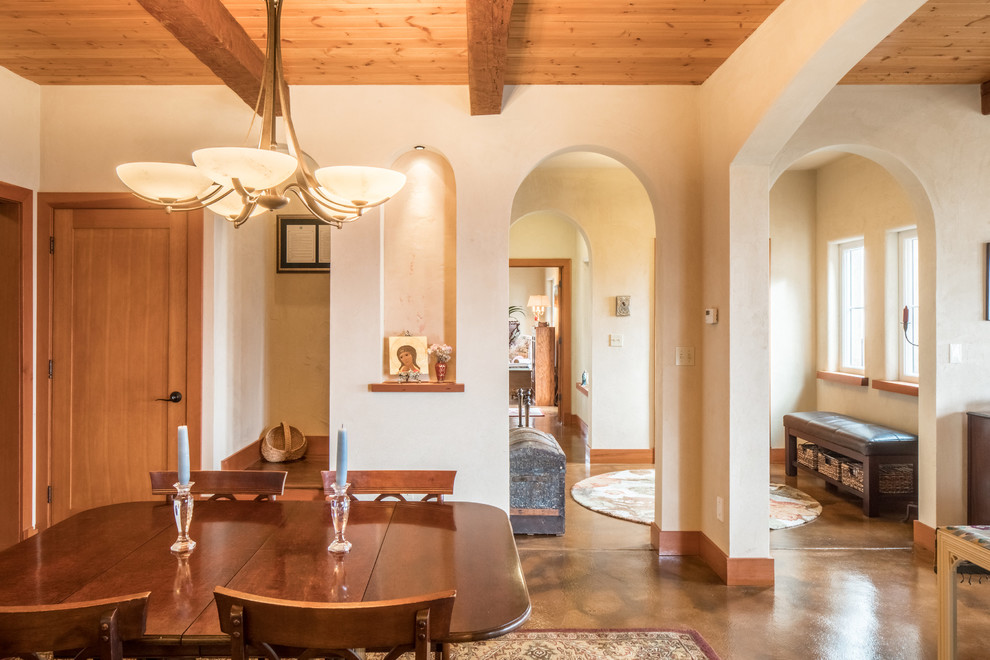 Idee per una sala da pranzo aperta verso la cucina mediterranea di medie dimensioni con pareti arancioni, pavimento in cemento, camino classico, cornice del camino piastrellata e pavimento marrone