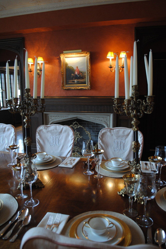 This is an example of a classic dining room in Kansas City with a stone fireplace surround and red walls.