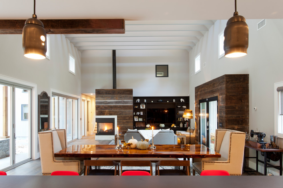 Ispirazione per una sala da pranzo moderna con pareti bianche, pavimento in legno massello medio, camino bifacciale e cornice del camino in legno