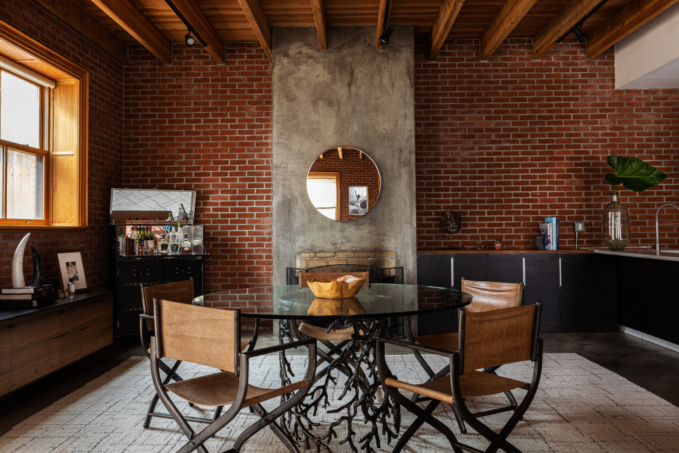 Foto di una sala da pranzo aperta verso il soggiorno industriale con pavimento in cemento, pavimento grigio, travi a vista, soffitto in legno e pareti in mattoni