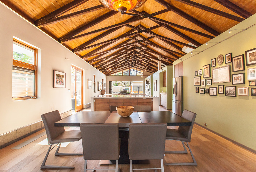 Exemple d'une salle à manger ouverte sur le salon rétro avec un mur vert et un sol en bois brun.