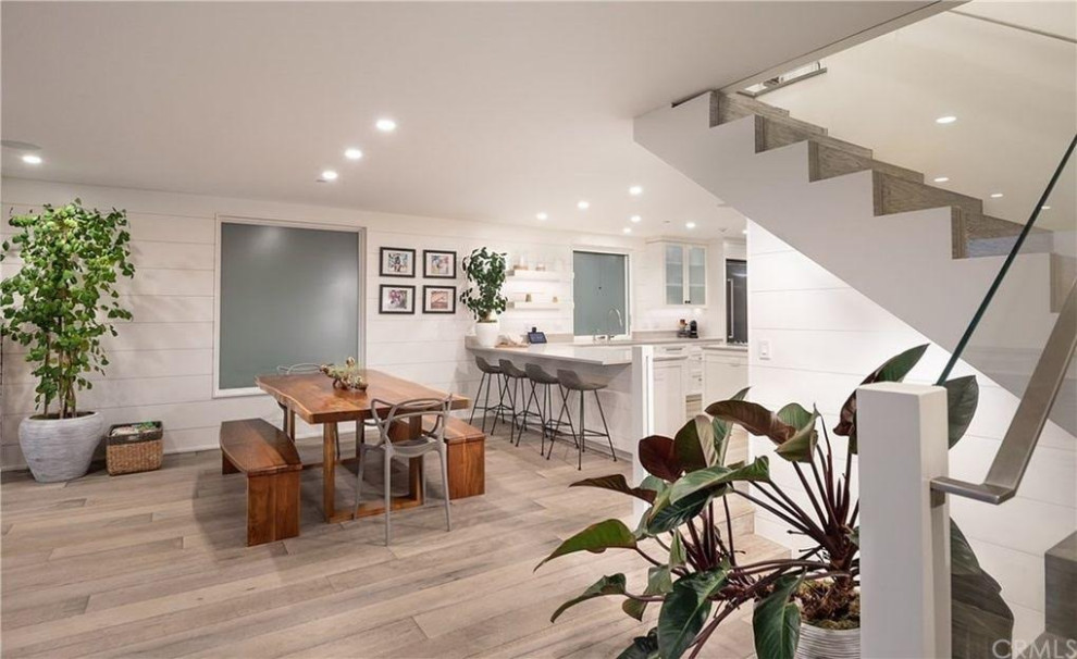 Immagine di una piccola sala da pranzo aperta verso la cucina minimal con pareti bianche, pavimento in legno massello medio, pavimento grigio e pareti in perlinato