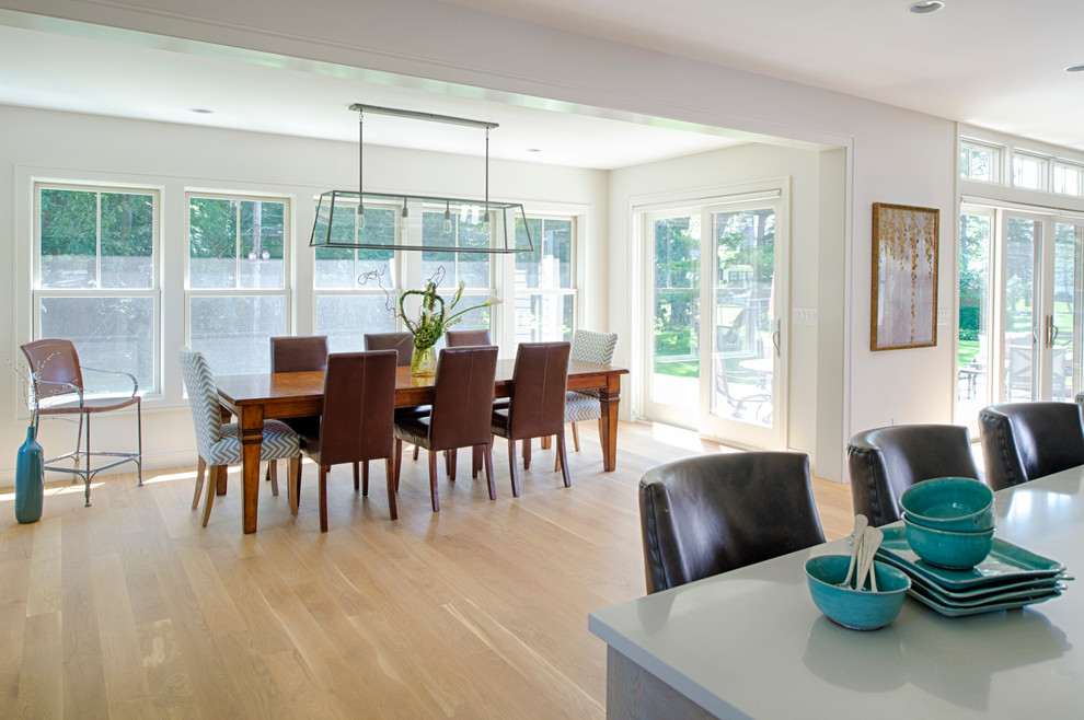 Immagine di una sala da pranzo aperta verso la cucina costiera con pareti bianche e parquet chiaro