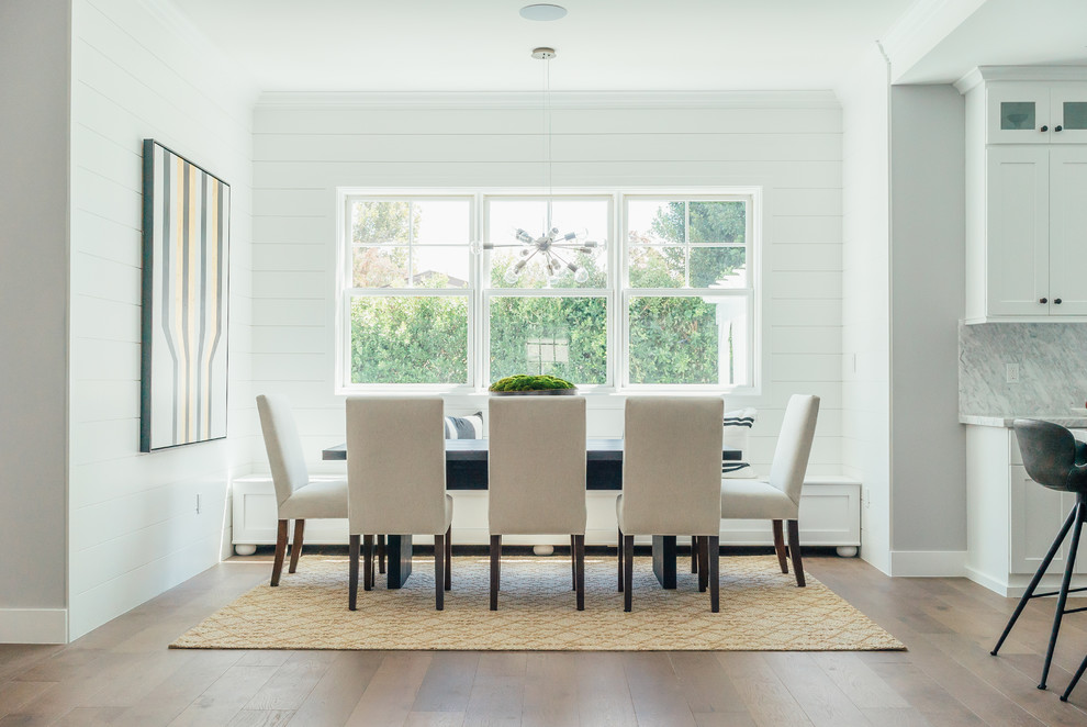 Immagine di una sala da pranzo aperta verso la cucina stile marinaro con pareti bianche, nessun camino e pavimento in legno massello medio