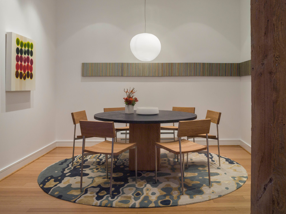 Immagine di una piccola sala da pranzo aperta verso la cucina contemporanea con pareti bianche, parquet chiaro e pavimento marrone