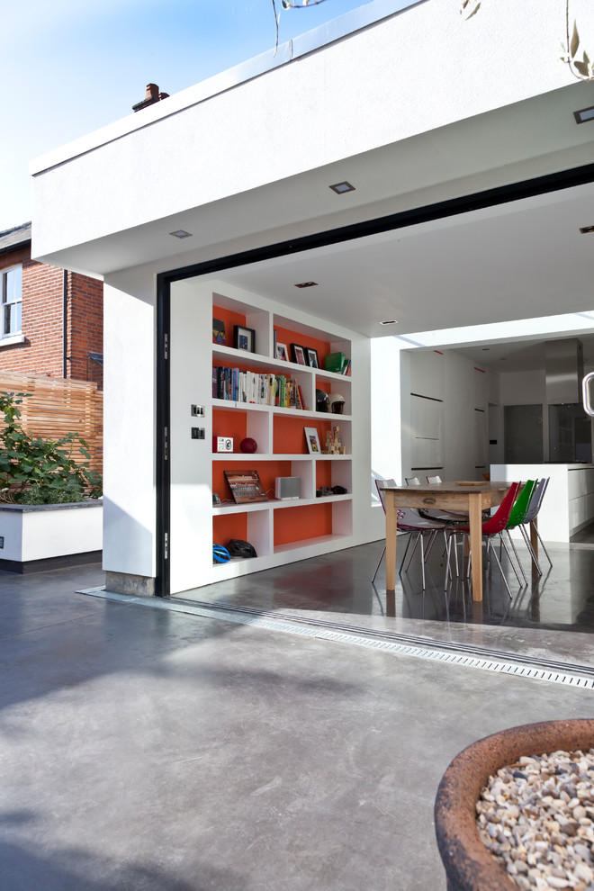 На фото: кухня-столовая среднего размера в стиле модернизм с белыми стенами, бетонным полом и серым полом без камина