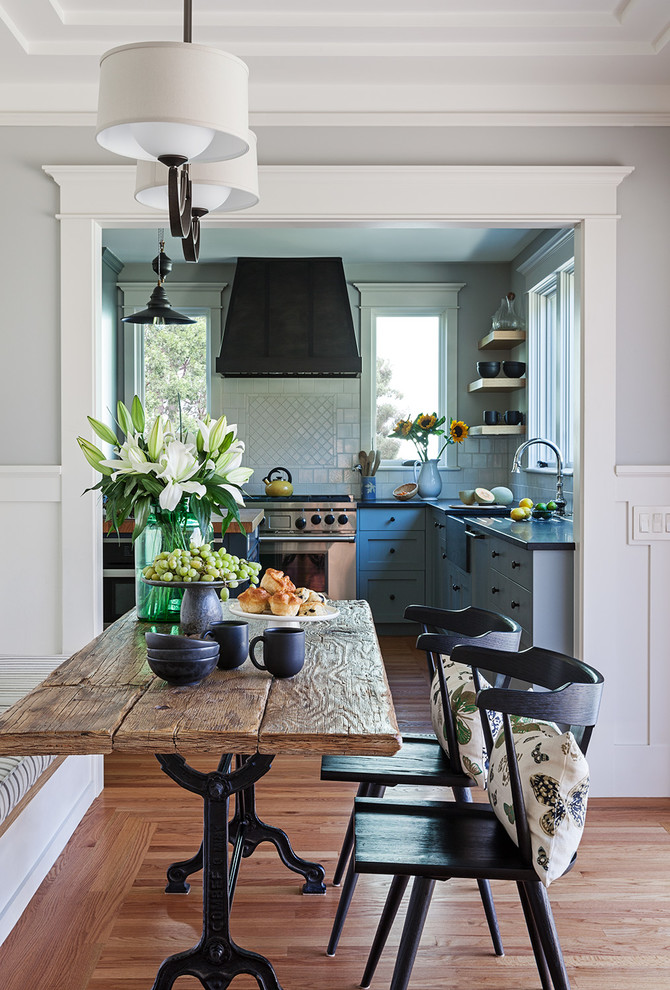 Cette photo montre une salle à manger ouverte sur la cuisine craftsman de taille moyenne avec un mur gris, un sol en bois brun, aucune cheminée et un sol marron.