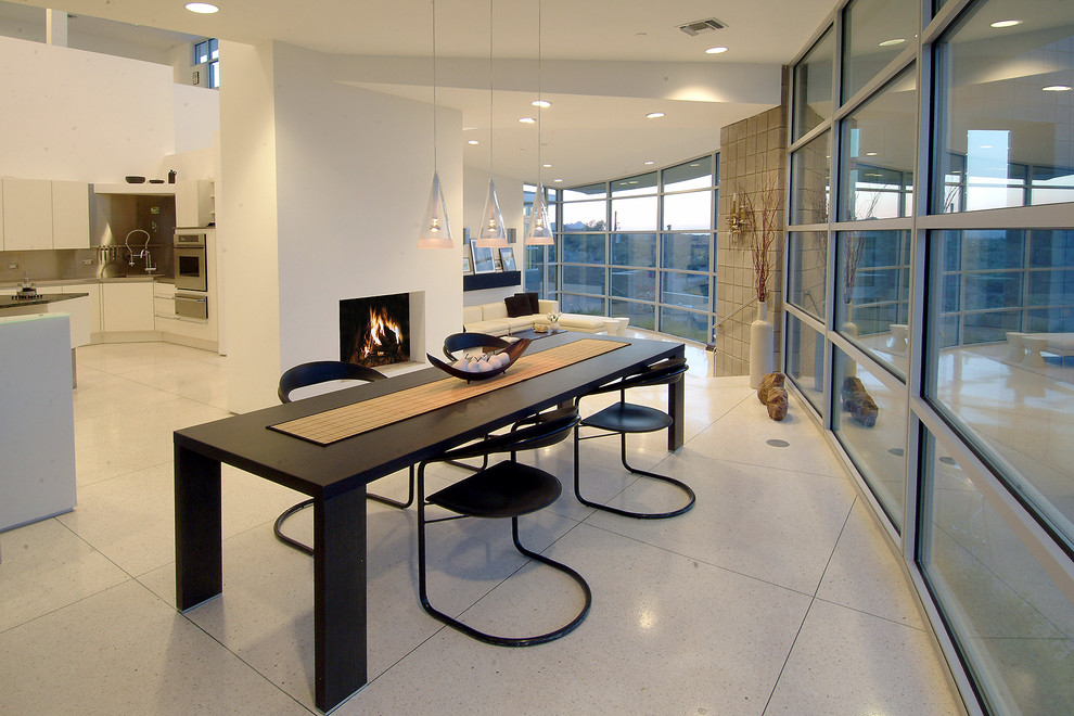 Inspiration pour une salle à manger ouverte sur le salon design avec un mur blanc, une cheminée standard et un sol en carrelage de céramique.
