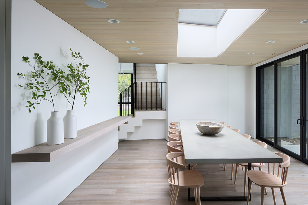 Inspiration pour une salle à manger minimaliste avec un mur blanc, parquet clair et un sol beige.