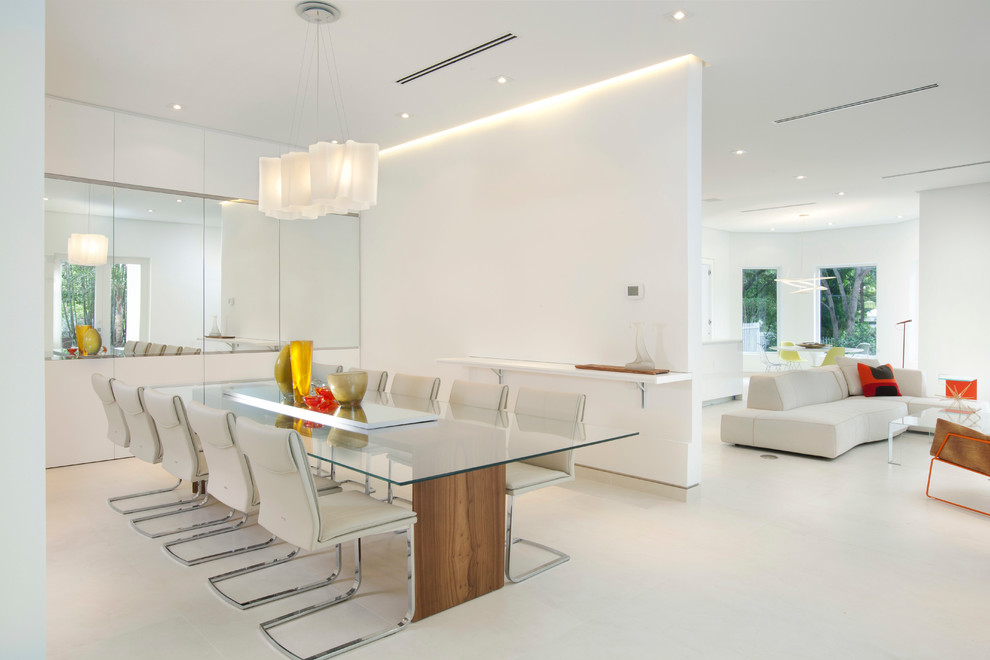 Modern open plan dining room in Miami with beige floors and feature lighting.