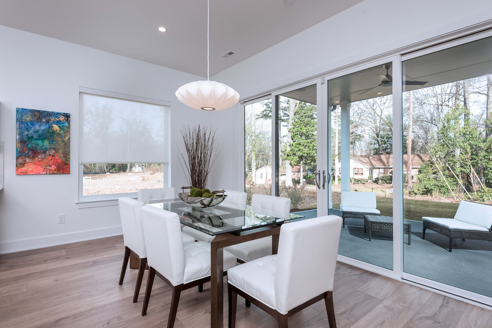 Example of a mid-sized trendy laminate floor and brown floor kitchen/dining room combo design in Charlotte with white walls