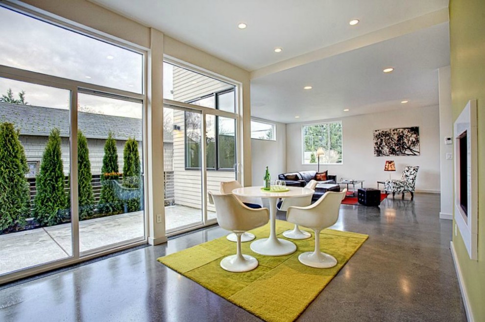 Стильный дизайн: гостиная-столовая среднего размера в стиле модернизм с зелеными стенами, бетонным полом, стандартным камином и фасадом камина из штукатурки - последний тренд