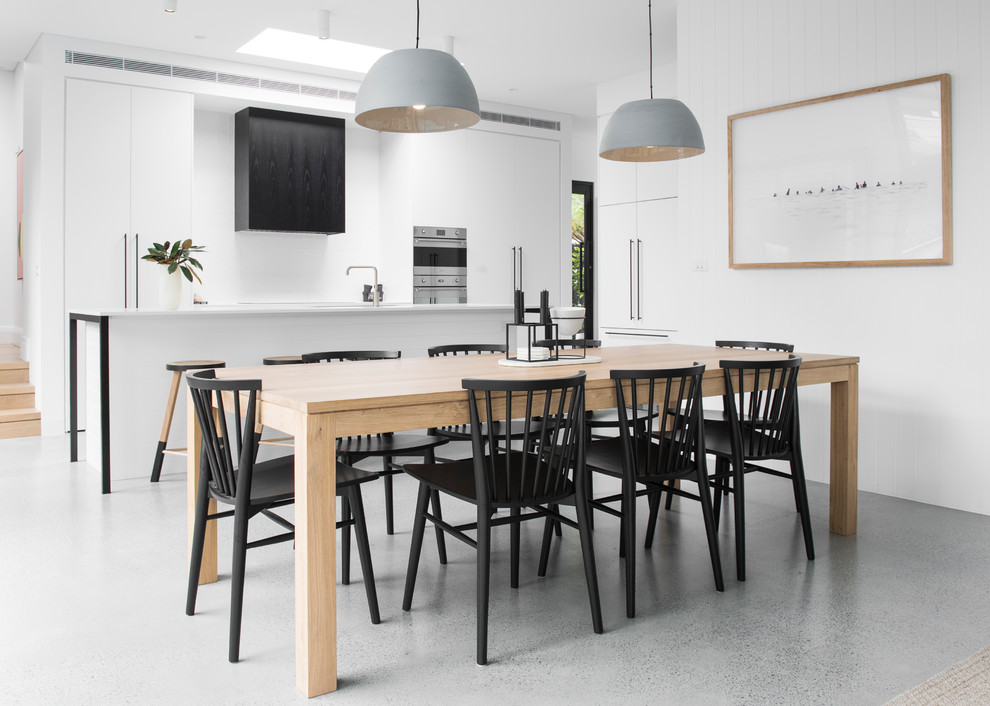 Idée de décoration pour une grande salle à manger ouverte sur la cuisine minimaliste avec sol en béton ciré, un sol gris et un mur blanc.