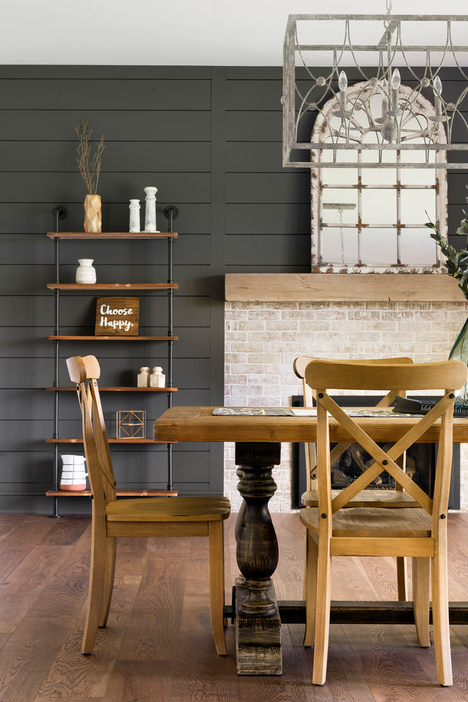Foto de comedor de cocina campestre de tamaño medio con paredes negras, suelo de madera en tonos medios, todas las chimeneas, marco de chimenea de ladrillo y suelo marrón