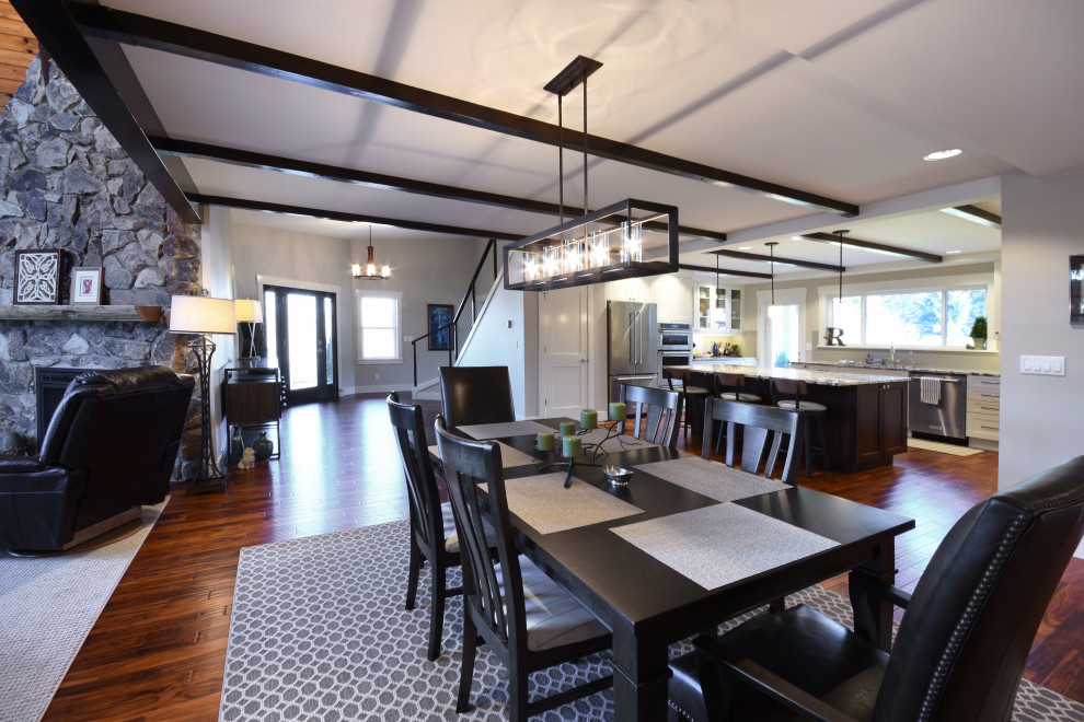 Large farmhouse open plan dining room in Seattle with white walls, dark hardwood flooring, a standard fireplace, a stone fireplace surround and brown floors.