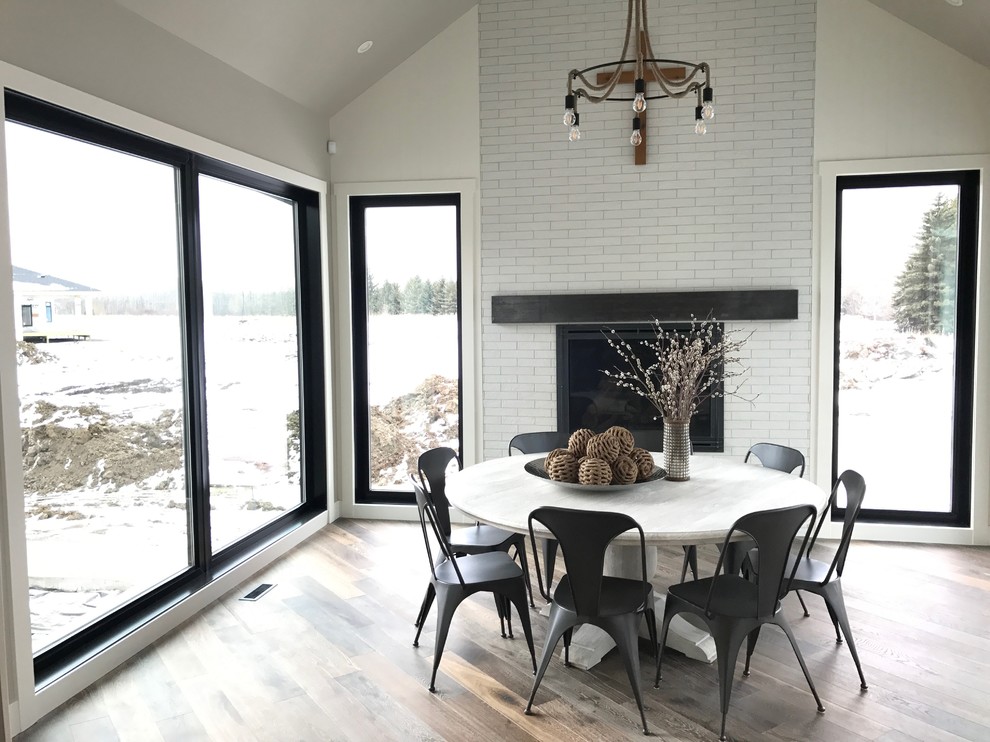 Inspiration for a large industrial open plan dining room in Edmonton with medium hardwood flooring, a standard fireplace, a brick fireplace surround and brown floors.