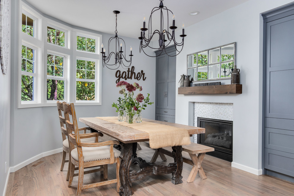 Inspiration for a farmhouse dining room in Seattle with grey walls, medium hardwood flooring, a standard fireplace, a tiled fireplace surround and brown floors.