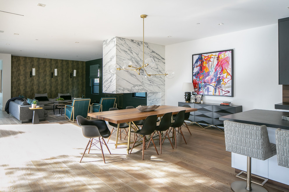 Esempio di una sala da pranzo aperta verso il soggiorno minimal con pareti bianche, pavimento in legno massello medio, camino bifacciale e pavimento marrone