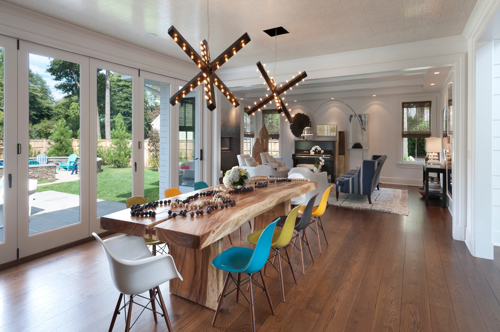 Cette image montre une grande salle à manger ouverte sur le salon design avec un sol en bois brun et un mur blanc.