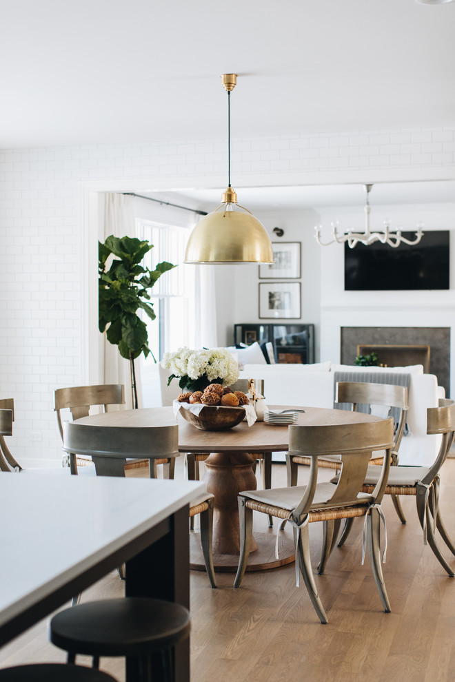 Cette photo montre une grande salle à manger ouverte sur la cuisine chic avec un mur blanc, un sol marron et parquet clair.