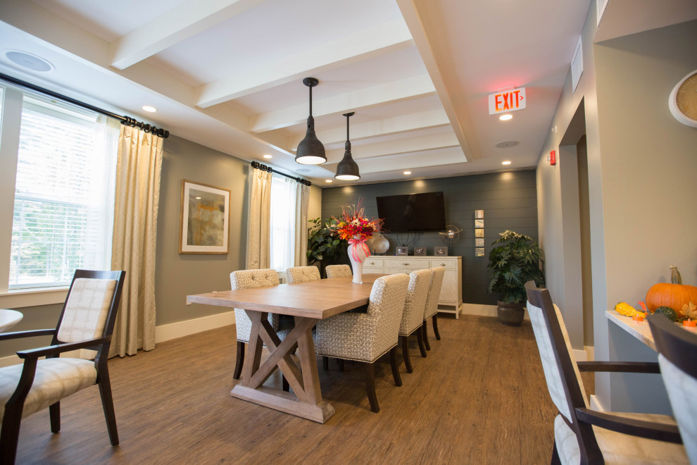 Aménagement d'une grande salle à manger ouverte sur la cuisine campagne avec un mur gris, un sol en bois brun, aucune cheminée et un sol marron.