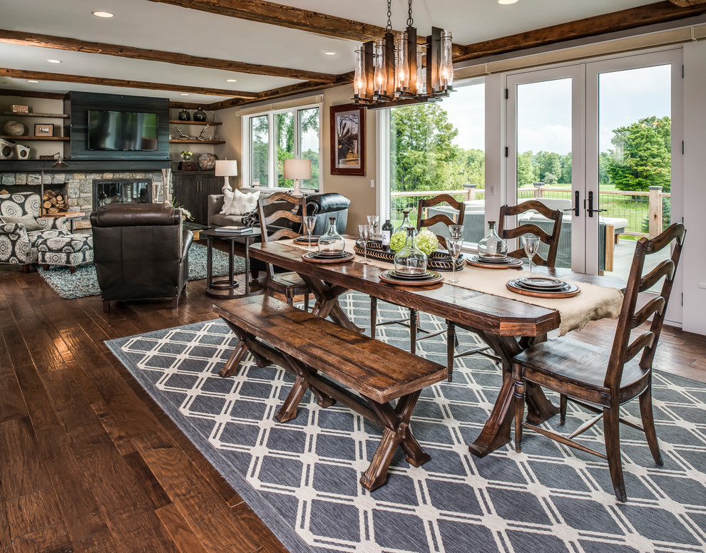 Country open plan dining room in Other with beige walls, dark hardwood flooring, a standard fireplace, a stone fireplace surround and brown floors.