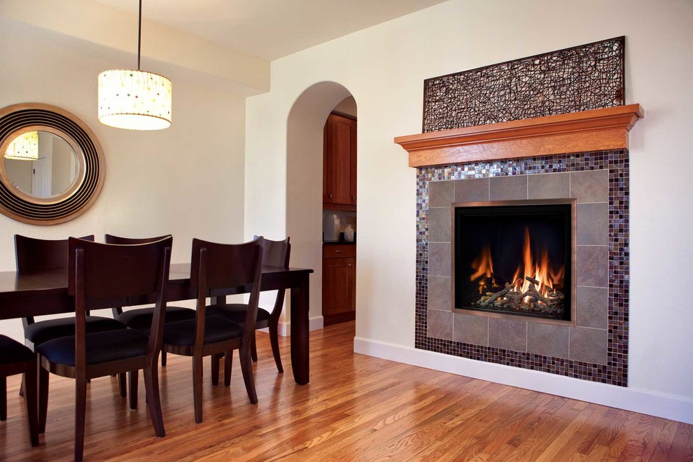 Medium sized contemporary enclosed dining room in Seattle with beige walls, medium hardwood flooring, a hanging fireplace, a tiled fireplace surround and brown floors.