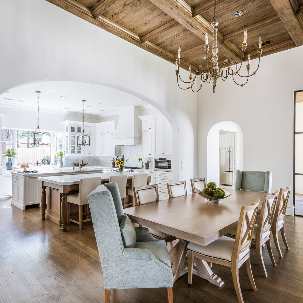 This is an example of an open plan dining room in Dallas with white walls and light hardwood flooring.