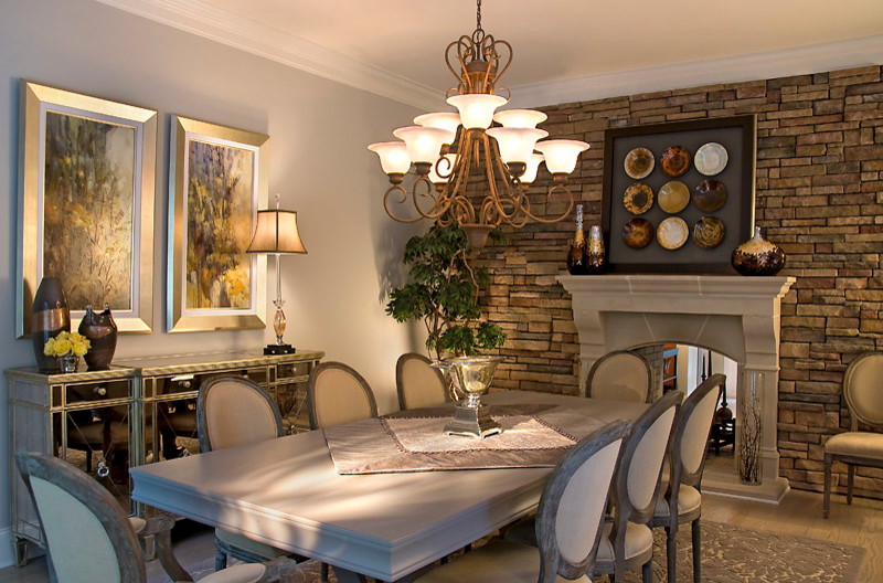 На фото: большая кухня-столовая в классическом стиле с серыми стенами, светлым паркетным полом, двусторонним камином и фасадом камина из камня с