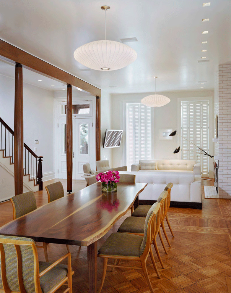 Cette image montre une salle à manger ouverte sur le salon design avec un mur blanc et un sol en bois brun.