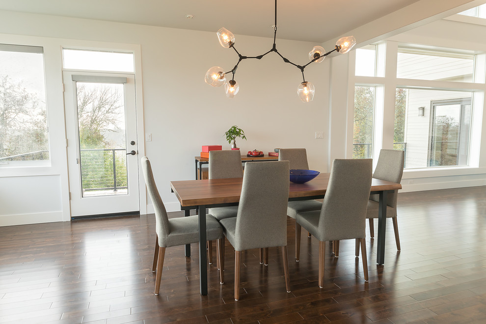 Idée de décoration pour une salle à manger ouverte sur la cuisine minimaliste avec un mur blanc, parquet foncé et un sol marron.