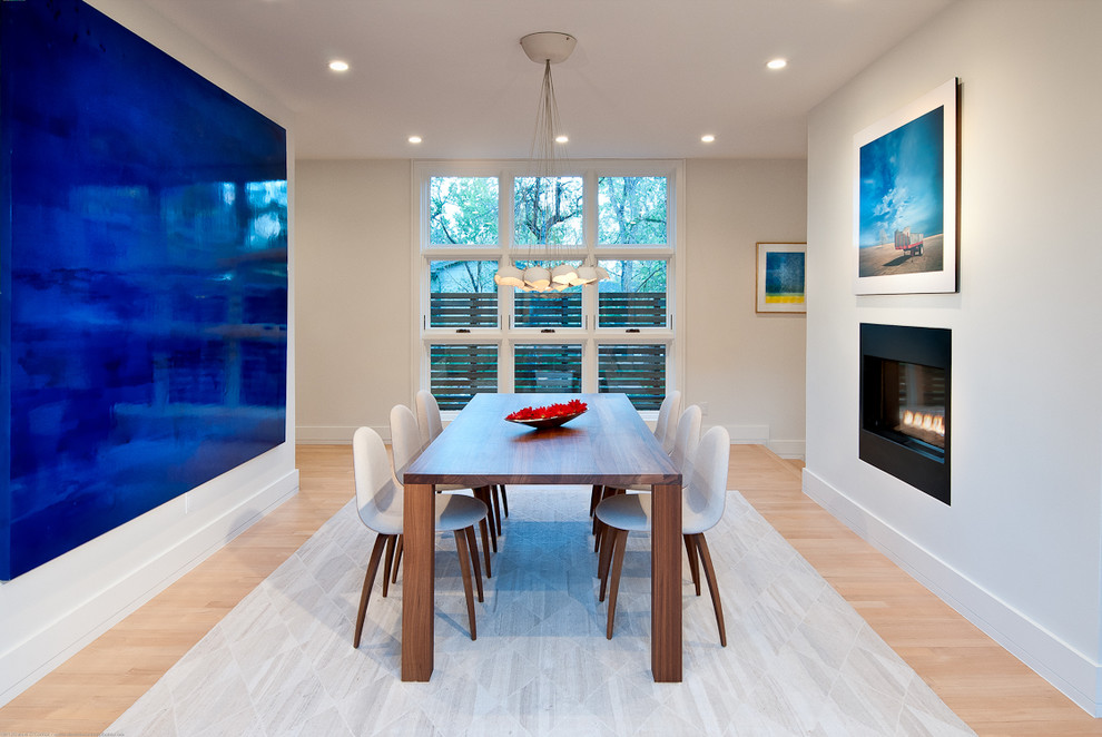 Example of a large trendy light wood floor kitchen/dining room combo design in Los Angeles with white walls, a two-sided fireplace and a metal fireplace